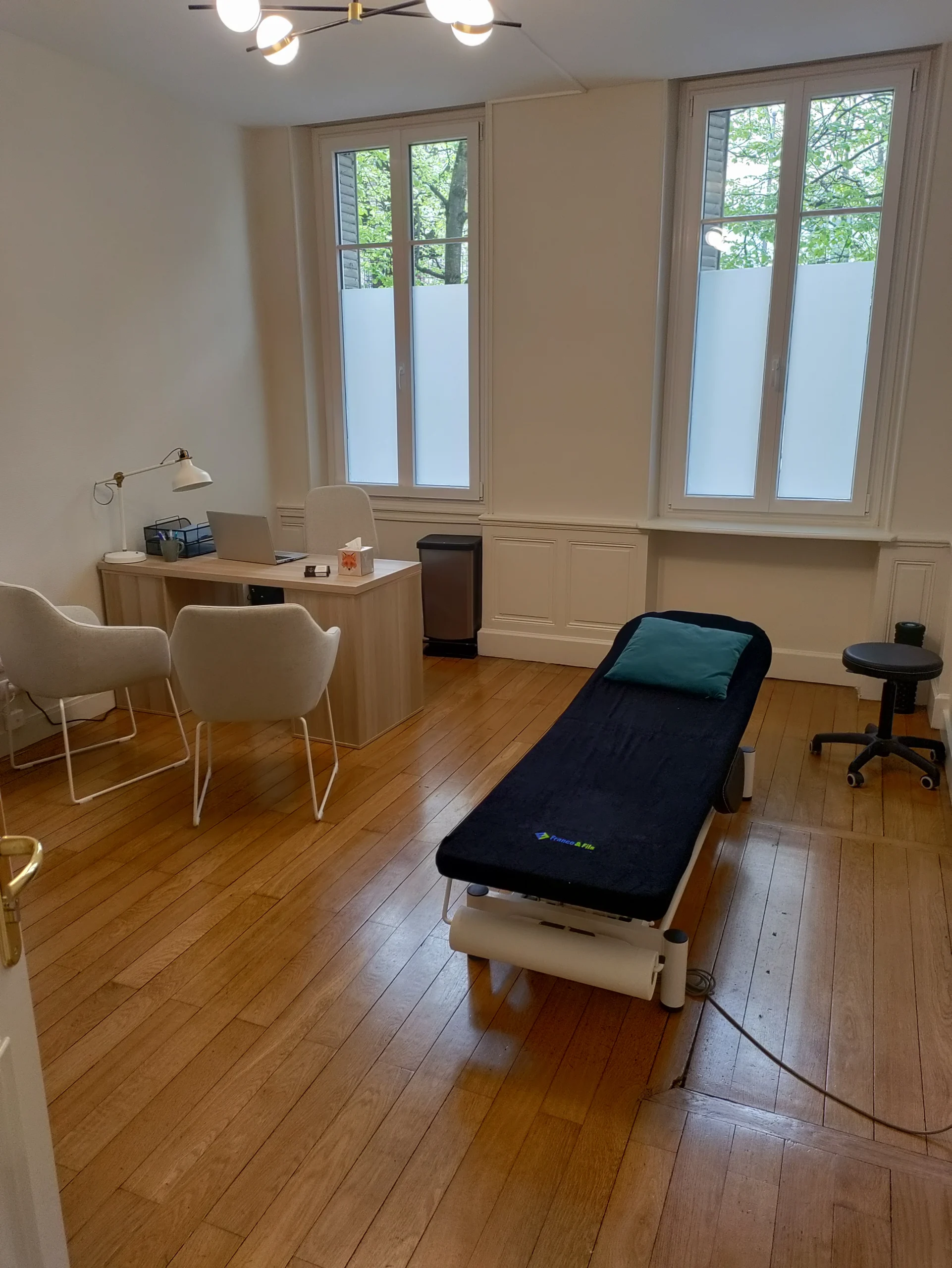 Salle de consultation d’ostéopathie à Dijon, lumineuse et apaisante, avec table de soins confortable, décoration sobre et ambiance chaleureuse propice à la détente et au bien-être des patients.